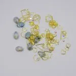 Gemischter Nagelschmuck, grosse und kleine Steine, kleine Perlen, Muscheln und Metallverzierungen.