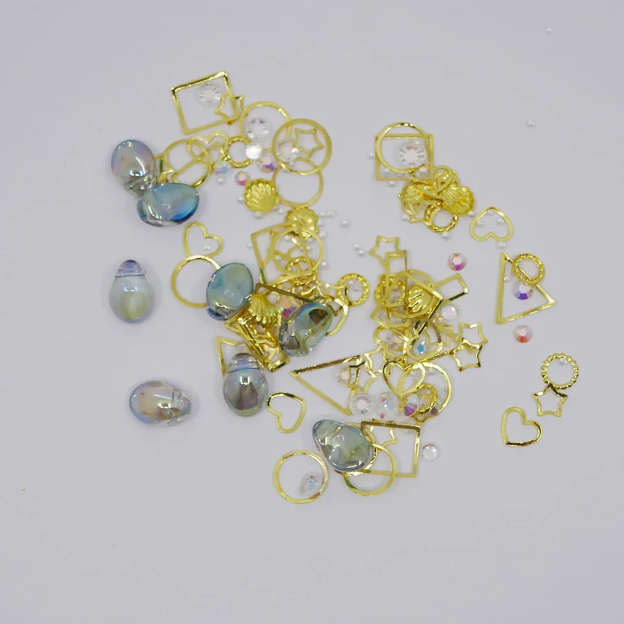 Gemischter Nagelschmuck, grosse und kleine Steine, kleine Perlen, Muscheln und Metallverzierungen.