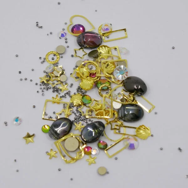 Gemischter Nagelschmuck, grosse und kleine Steine, kleine Perlen, Muscheln und Metallverzierungen.